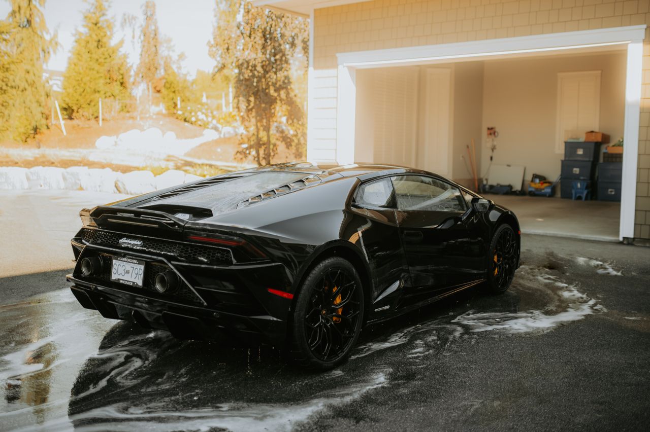 services-01 High-end Lamborghini sports car being washed at a sunny outdoor location.