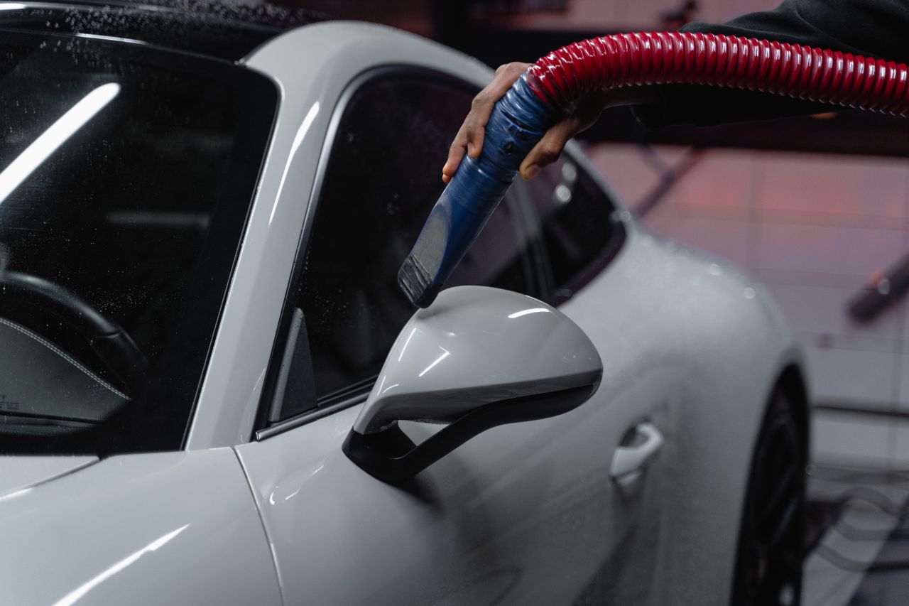 services-03 A white sports car is meticulously vacuumed indoors for a flawless shine and maintenance.