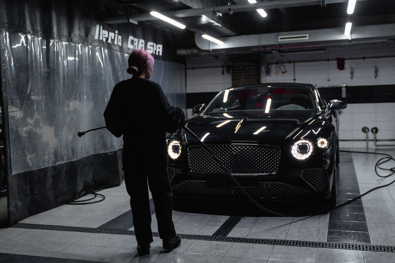 why-choose-us A luxury car being washed inside a car service garage by a professional.